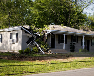 A residential home in Nampa, ID, with significant structural damage to the roof and siding caused by a fallen tree during a storm.